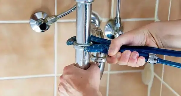 Photo of plumber working on bottom of sink